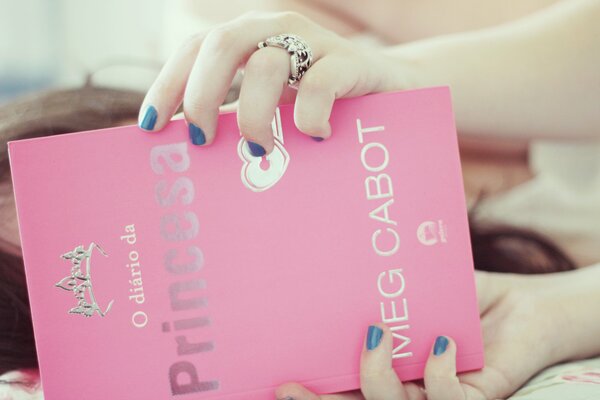 Una mujer sostiene un libro rosa en sus manos