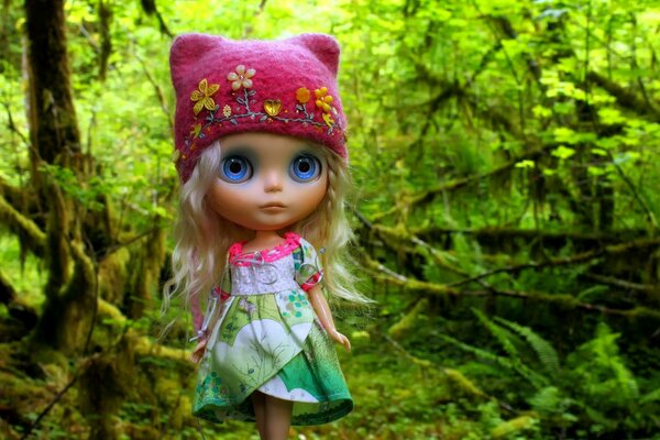 Doll in the forest in a pink hat