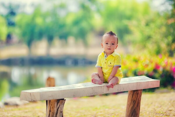Kleiner Junge, der auf einer Bank sitzt