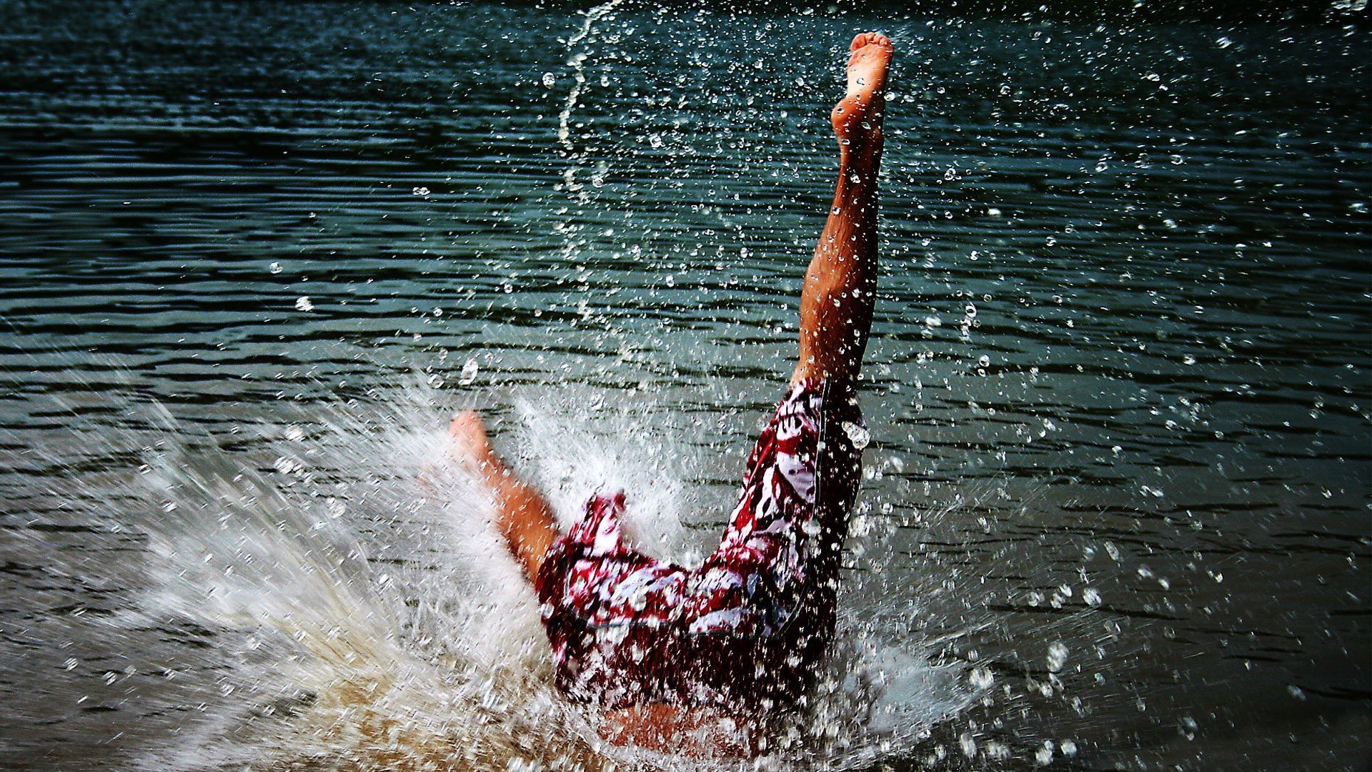 Свободное падение в воде. Девушка в брызгах воды. Человек, падающий втводу. Прыжок в реку. Ныряет в воду.