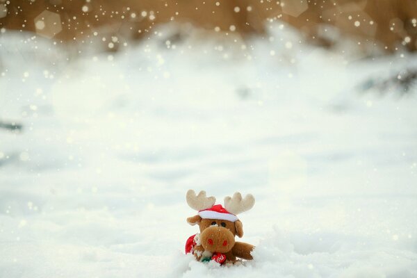 A toy deer in a hat in the snow