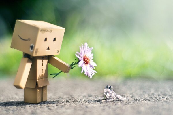 Cardboard robot gives a flower to a glass frog