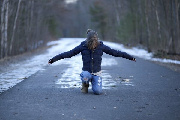 A girl is sitting on a snowy road