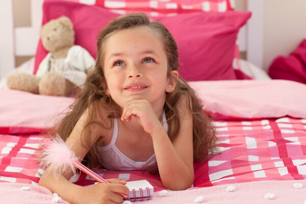 Dreamy girl with a teddy bear and a notebook