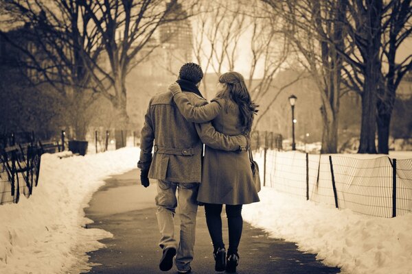 Couple in the park on the path in winter lanterns