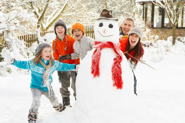 Foto familiar divertida de invierno en el muñeco de nieve