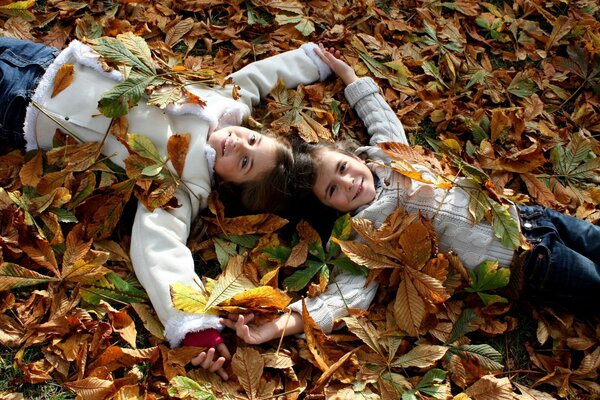 Happy children lie on autumn leaves