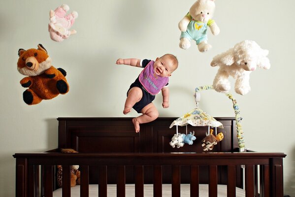 Baby jumps with toys in the crib