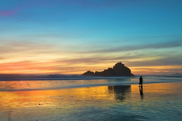 Bei Sonnenuntergang geht ein Liebespaar am Strand spazieren