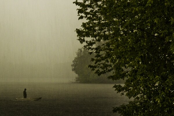 Silhouette in einem Boot auf einem See an einem regnerischen Abend