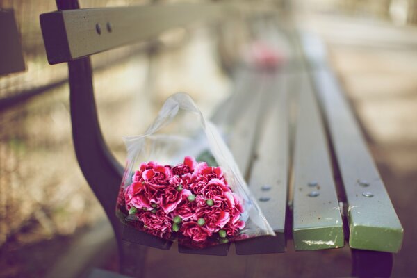 A bouquet of flowers is lying on a bench