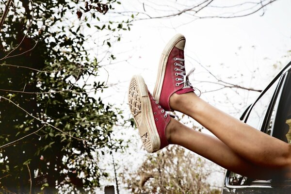 Image of legs in red sneakers against a background of bushes