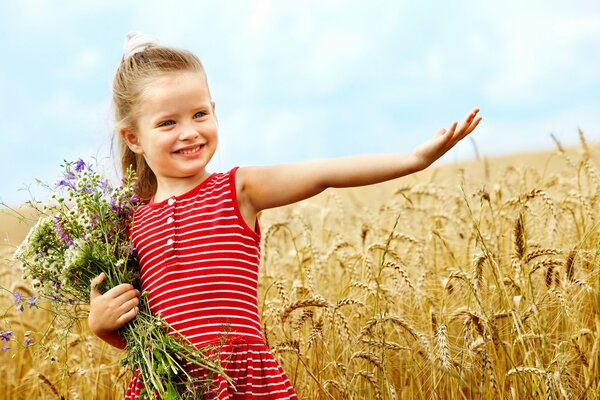 Милая маленькая девочка с цветами в пшеничном поле