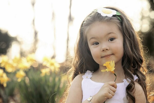 A little girl with a yellow daffodil in her hand