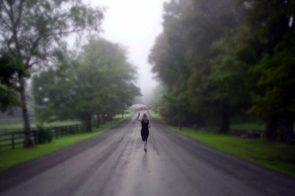 Ein Mädchen mit einem Regenschirm geht die Straße entlang