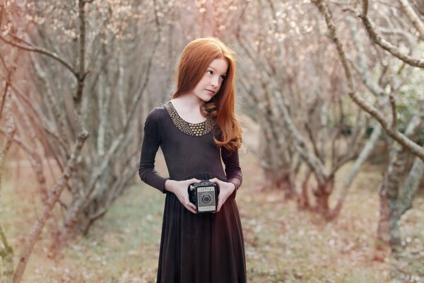 Schönes Mädchen mit einer Kamera im Kleid