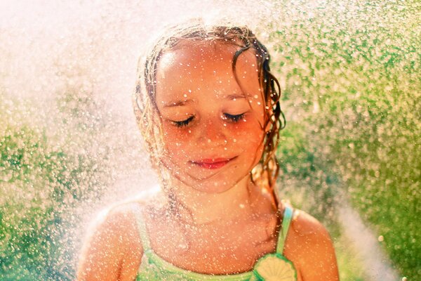 Niña con los ojos cerrados bajo la lluvia