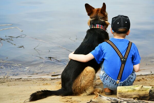 Junge umarmt Hund am Seeufer