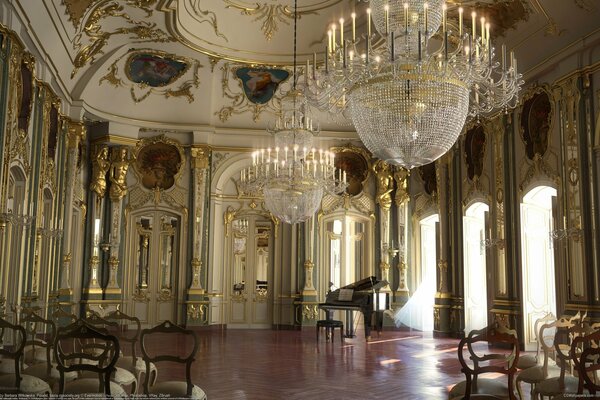 Place du palais de la salle avec des colonnes , des lustres, un piano à queue