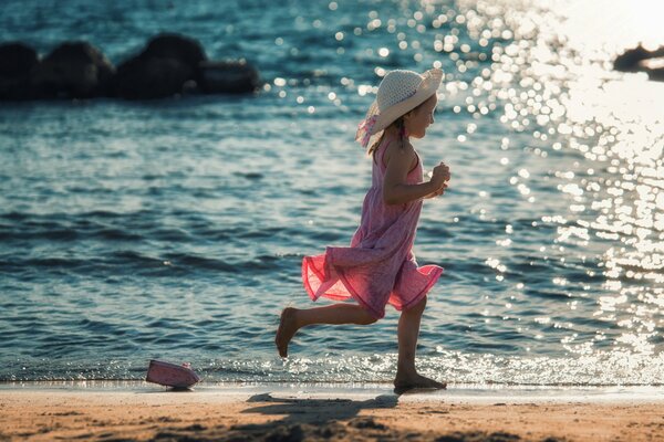 A girl runs along the shore after a boat