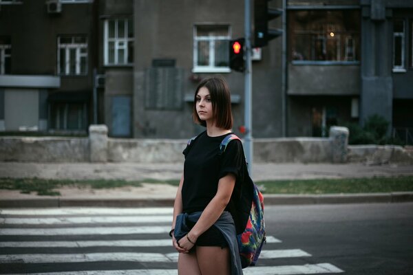 Chica solitaria en la ciudad en un semáforo