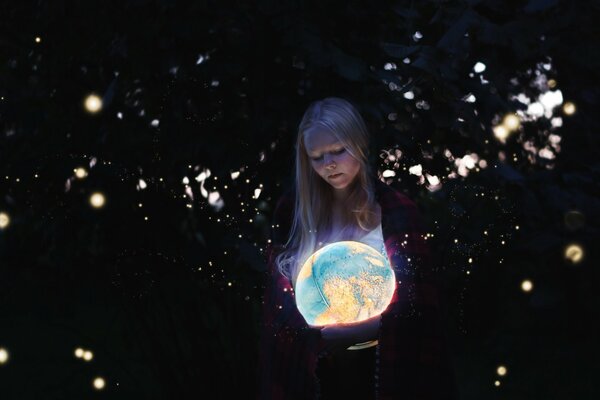 Jeune fille blonde avec un globe brillant dans les mains