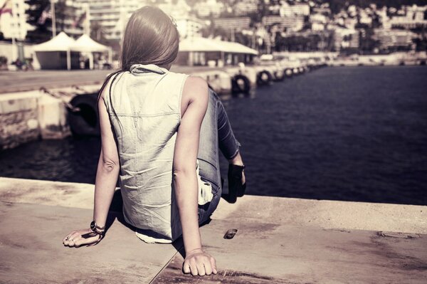 Chica sentada en el muelle de la ciudad