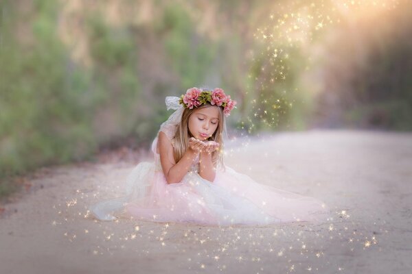 Una bambina in un abito da ballo sulla strada fa la magia