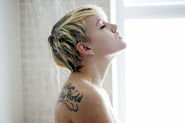 Młoda dziewczyna z tatuażem pod prysznicem