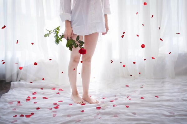 Chica de pie en la cama con una rosa