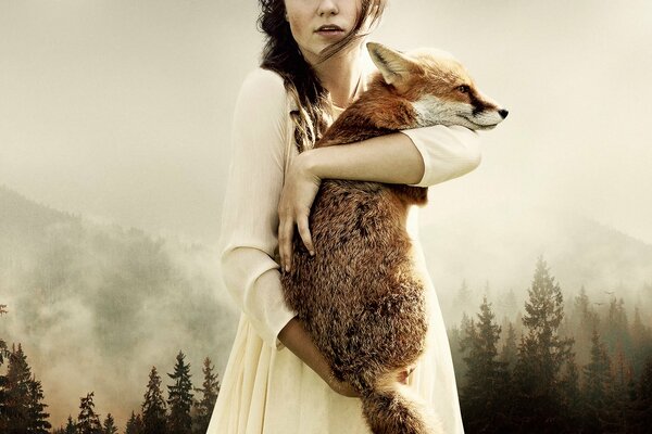A girl holds a fox against the background of the forest