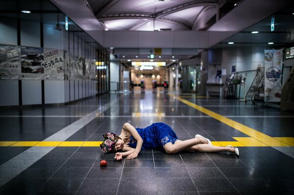 Ragazza sdraiata in un vestito blu sul pavimento con una mela