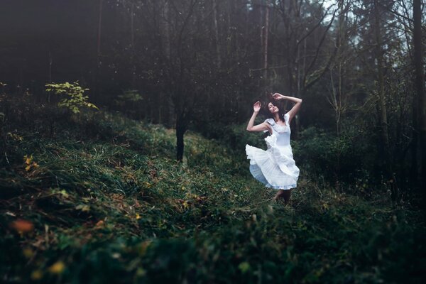 A girl in a white dress dancing in the forest