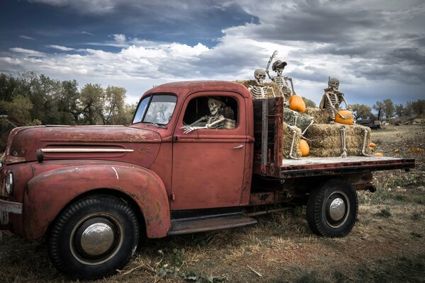 Gli scheletri di Halloween guidano in un camion di zucche e fieno