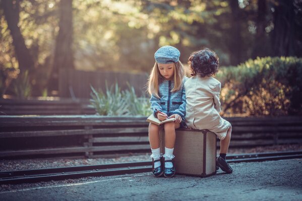 Niños lindos sentados en una maleta