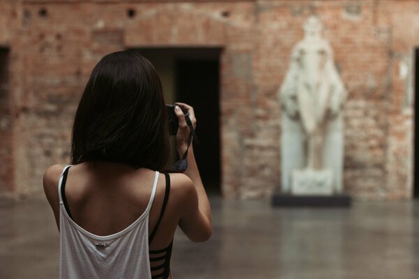 Ein Mädchen mit einem kurzen Haarschnitt fotografiert eine Statue