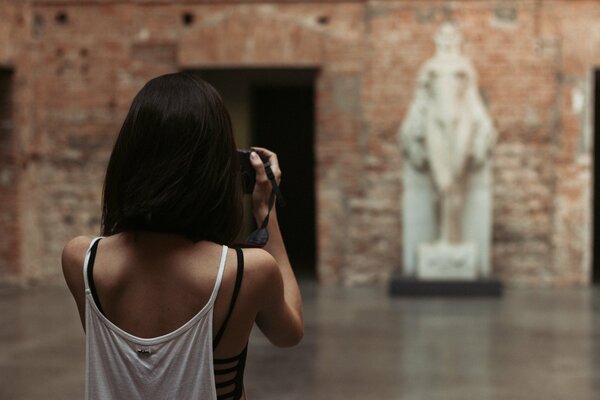 Une fille aux cheveux courts prend des photos d une statue