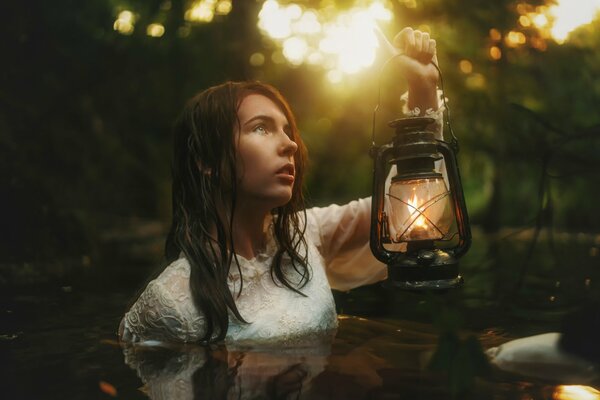 Ragazza in acqua con la lanterna di notte nel lago