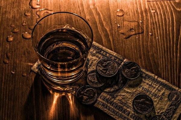 Mesa con una pila de alcohol con monedas y un Dólar