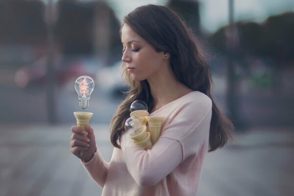 A beautiful girl holding a light bulb with the power of her mind