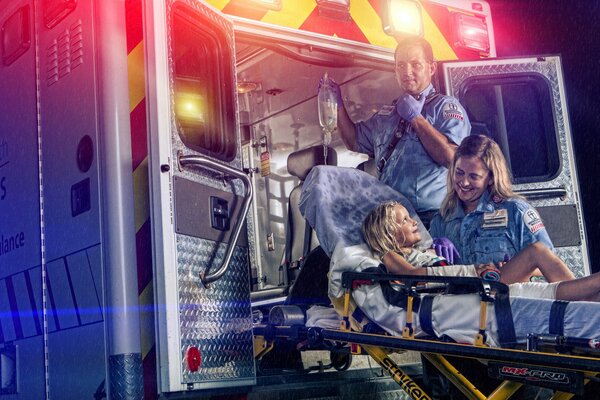 Ein kleines Mädchen wird mit einem Rollator in einen Krankenwagen transportiert