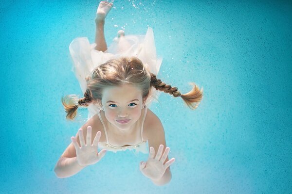 Una niña con coletas nadando bajo el agua. Feliz verano