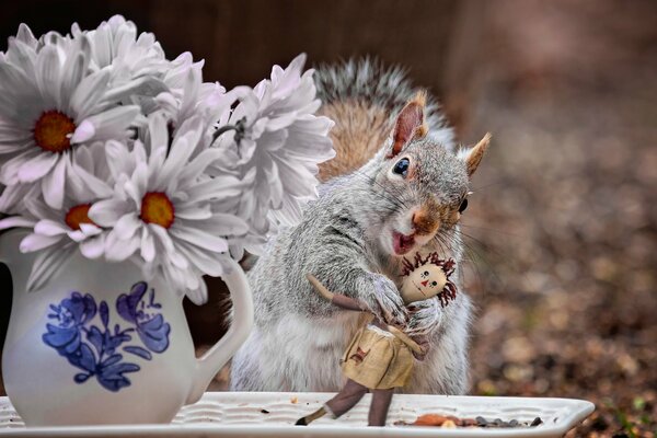 A squirrel is playing with a doll on a saucer