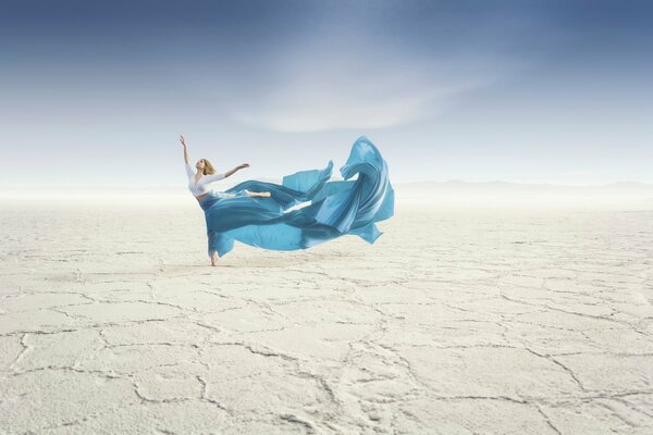 Chica bailando en el desierto con falda larga azul