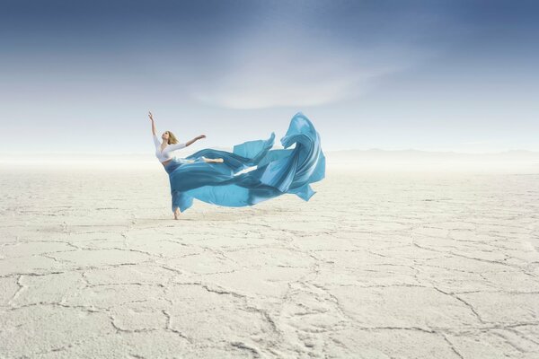 Танцующая девушка в пустыне с голубой длинной юбкой