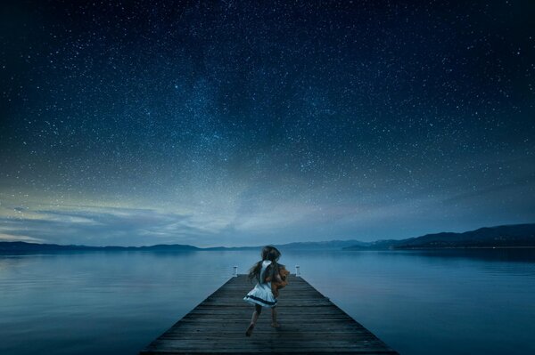 Ragazza sul molo nel cielo stellato