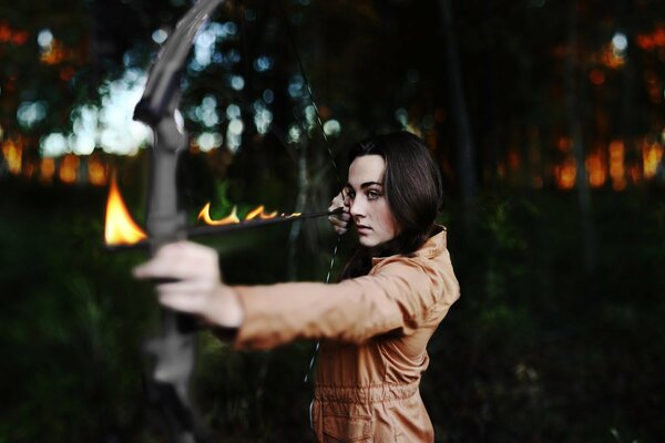 A girl shoots a burning arrow from a bow