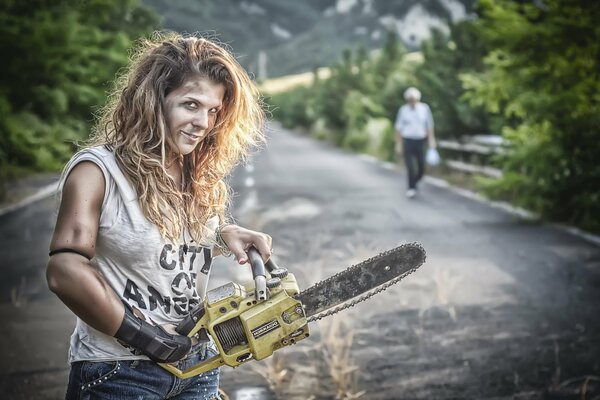 A girl in the hands with a chainsaw in the mountains