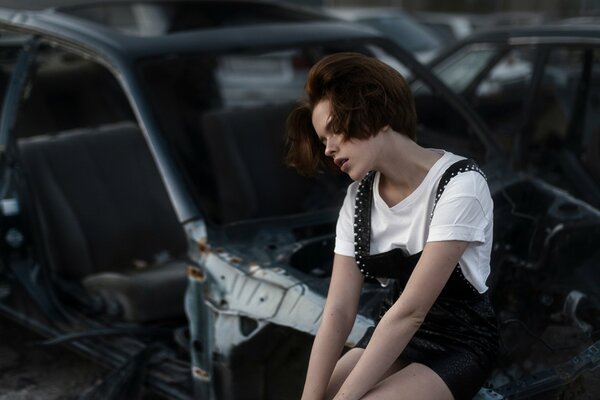 Fille à côté d une voiture démontée