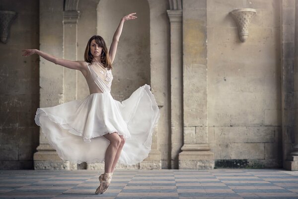 Beautiful ballerina in a white dress in an old building